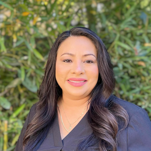Monica Segura smiling in front of a bush