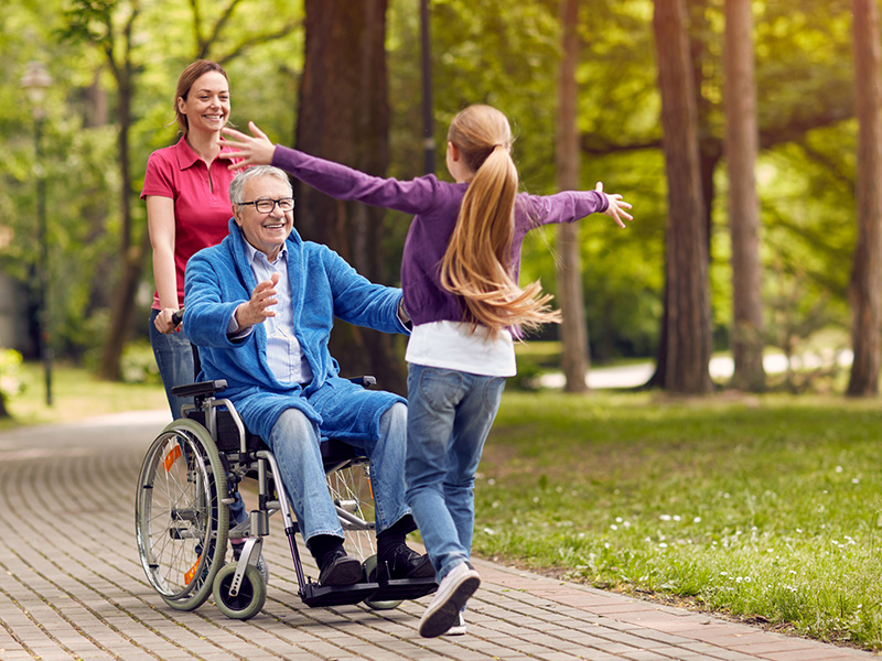Senior veteran in wheelchair enjoying time outdoors with family and caregiver