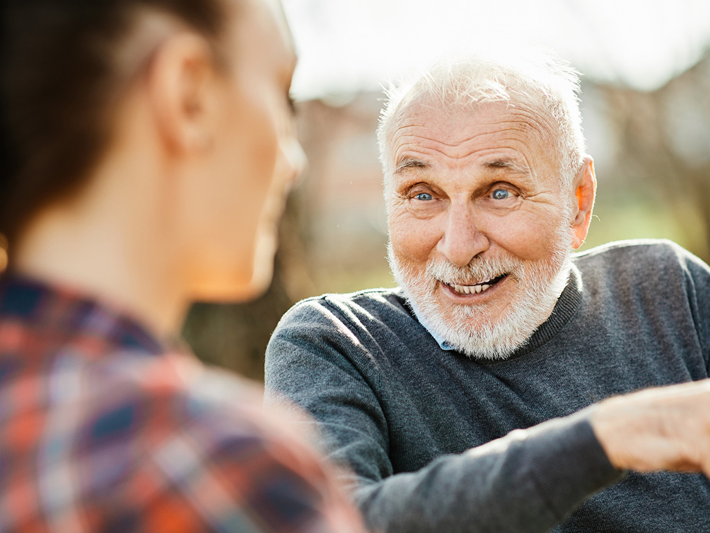 Senior veteran smiling and talking with caregiver during home visit