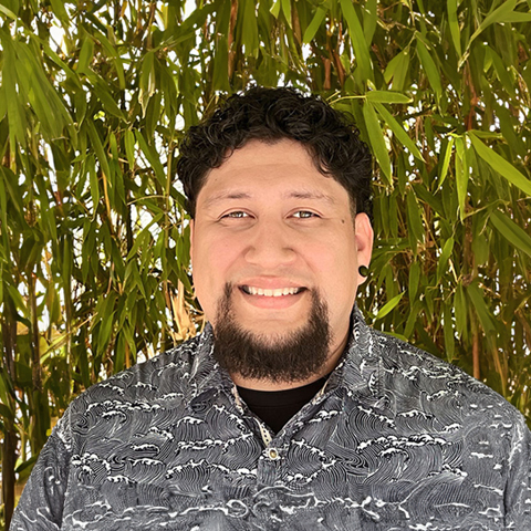 Eddie Perez smiling in front of a tree